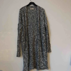  - Tunt gråspräckligt stickad kofta från hollister.  Går till knäna. Välanvänd och lite noppig, därav priset. Köparen står för frakt:)