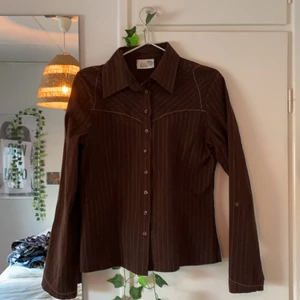 skjorta  - Brun skjorta med kroppsnära passform. storleken är L men skulle säga att den passar ej M om man vill ha tajtare passform och en S om man vill ha lite pösig passform.