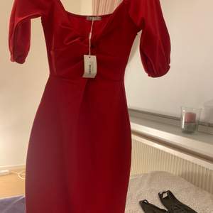 En röd klänning med en snöring i mitten aldrig använd prislapp finns kvar