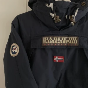 Napapijri skidjacka  - Säljer en superfin skidjacka från Napapijri, marinblå. I mycket fint skick! I anorakmodell. Kan mötas upp i Slussen/ T-Centralen Strl S