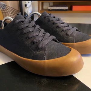 COS canavas sneakers, strl 44 - Ett par COS canvas-sneakers i storlek 44. Blått tyg, snygg rågummisula och detaljer på hälen i läder. Jag kan nog räkna på en hand de gånger jag använt dessa.   Skoblock ingår ej.  Titta gärna på mina övriga annonser. Samfraktar gärna 😊