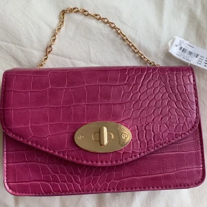 Väska - En rosa väska med guld detaljer från Glitter. Oanvänd och prislappen är på. 