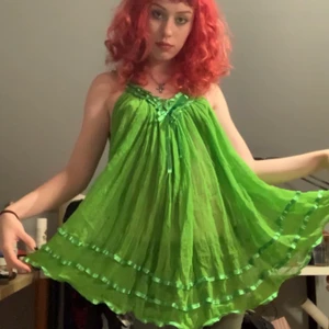 Grön Lingerie Klänning/Tunika - gullig lingerine klänning som kan användas som tunika. lätt genomskinlig med satinband som detaljer. köpt på beyond retro men knappt använd av mig. 82cm som längst, 66cm som kortast (mätt från axlarna o ner). har ett litet hål jag kan skicka bild på