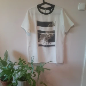  - Cool längre T-shirt från Forever 21. Benvit med tryck, kort dragkedja i ryggen och svart krage. Lätt creppat tyg och slutar under rumpan. Fint begagnat skick.  Göteborg/kan skickas. 