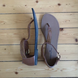  - Sandal i brun skinnimitation. Använda vid endast ett tillfälle. 