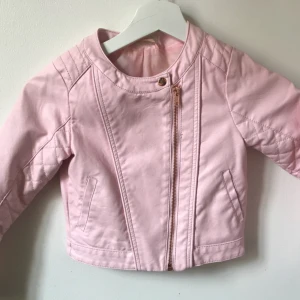  - En fin rosa skinnjacka, storlek 122.  Har några små skrapmärken vid sidan av armen, annars i gott skick.