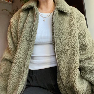 Grön teddyjacka, knappt använd! - Jättefin grön färg, silvrig dragkedja. Köpt i London förra vintern, bra skick! Frakt tillkommer ✨ Budgivning i kommentarerna!