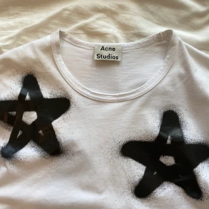 Acne tisha  - Såååå cool Vit t-shirt med svarta stjärnor från Acne, storlek XL men passar som typ oversized s