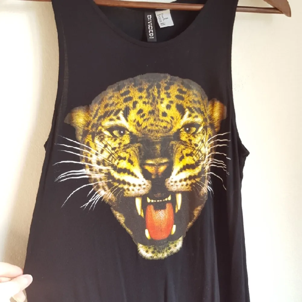 Svart knälång klänning med leopardmotiv framtill, i storlek 38. Något längre baktill. Oanvänd, endast prövad :). Klänningar.