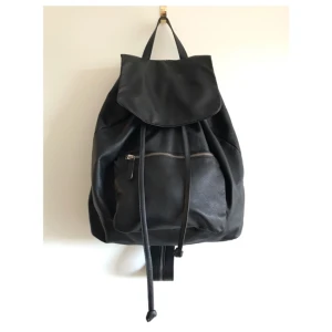  - Cool ryggsäck i äkta skinn från COS. Helt oanvänd. Dragsko, innerficka samt ytterficka. Går att dra ihop axelbanden så att den kan slängas över axeln. 