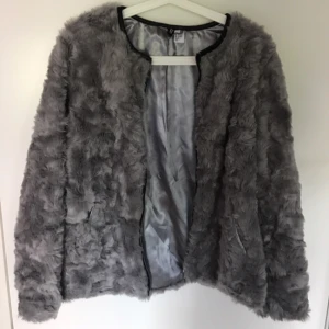  - Grå pälsjacka (fakepäls). Aldrig använd - väldigt bra skick! Säljer pga för stor för mig.