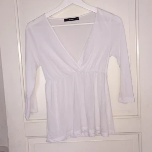  - Vit V-ringad tröja med trekvarts ärm i storleken XS. Tyget går omlott i ringningen. Använd endast en gång.