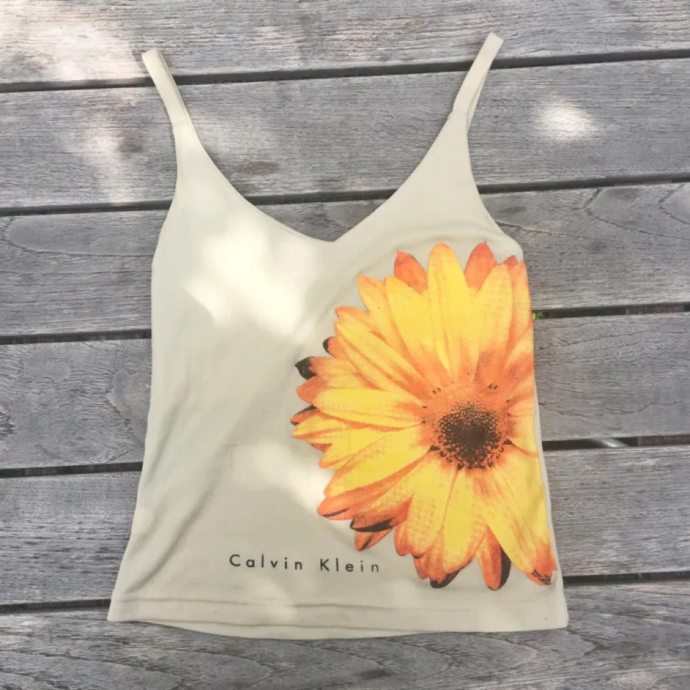 Calvin Klein-linne med blomma. Små slitningar, se sista bild. 50 kr inklusive frakt :). Toppar.