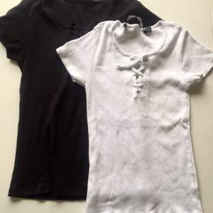 En svart och en vit ribbad t-shirt med snörning fram. Aldrig använda pga köpt för stor storlek.   Säljer båda för 50kr, en för 35kr.