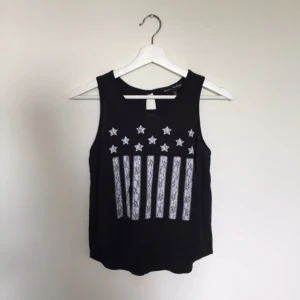  - Svart Linne med ett vitt tryck av USA flaggan. Linnet är i storlek S och kommer från firman Mason + Mackenzie. Den är köpt i affären Kohl's i USA och väl använd men fortfarande i ett mycket gott skick!