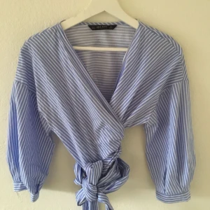  - Blårandig omlottblus. Kan knytas på många sätt och ger en snygg siluett! 