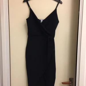  - Svart klänning från Nelly.com. Aldrig använd. Skuren snett vid benen. 