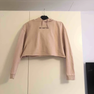 - En smuts rosa maghoodie med texten ”WE MATTER”