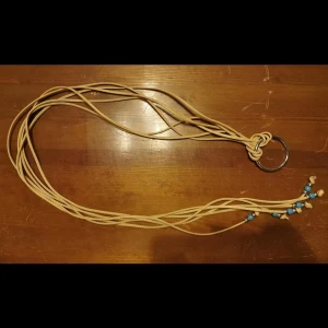 Bälte med remmar : fejk läder - Bälte gjord av remmar i fuskläder (tror jag). Längst ut på remmarna är det pärlor i silver och turkost.