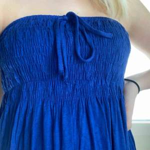 Söt blå klänning utan axelband. Man kan välja att knyta snöret runt halsen, som rosett eller gömma det innanför klänningen. Köparen står för frakten. Köpt i USA