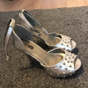  - Skor från DinSko, använd en gång. Färg: silver, glänsande  Storlek: 38 Klack: 10 cm