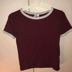  - Vinröd T-shirt med vita muddar på ärmar och krage. Bra passform och skön.