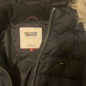  - Tommy Hilfiger vinterjacka. Använd men i bra skick. Nypris 2400. Köpare står för frakt (63 kr) 🥰 Fläcken som syns på bild 2 beror på kameran och sitter ej på jackan 