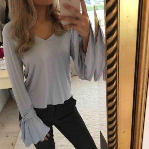  - Ljusblå tröja från Nelly. Fint skick. Superfina volangärmar med knytning!