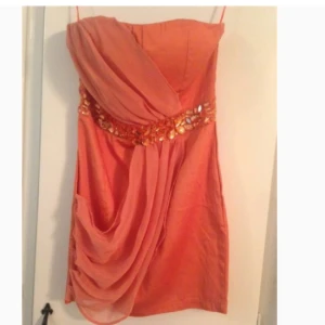  - Vacker klänning i korallfärg med stenar. Storlek 12. Aldrig använd 