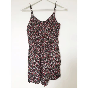  - Mjuk jumpsuit med fickor och knappar över bysten. 