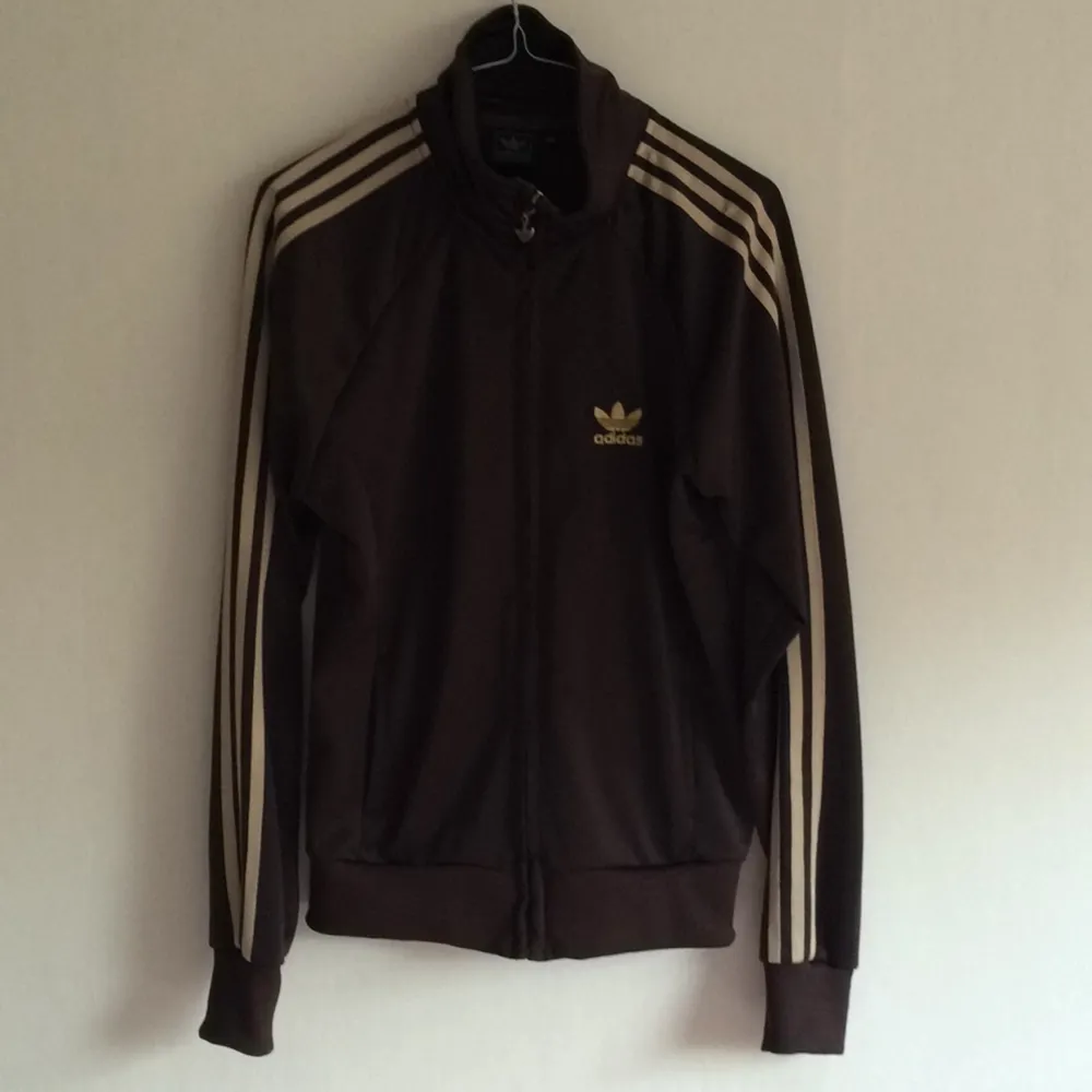 Mörkbrun adidas med guldiga ränder på armarna. Med dragkedja. 
Strl XL men skulle mer säga att det är en s eller m.. Hoodies.