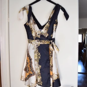  - Klänning av märket Elise Ryan. Silkigt materiel och mönster i svart/vitt/guld. Använd 1 gång, gott skick.