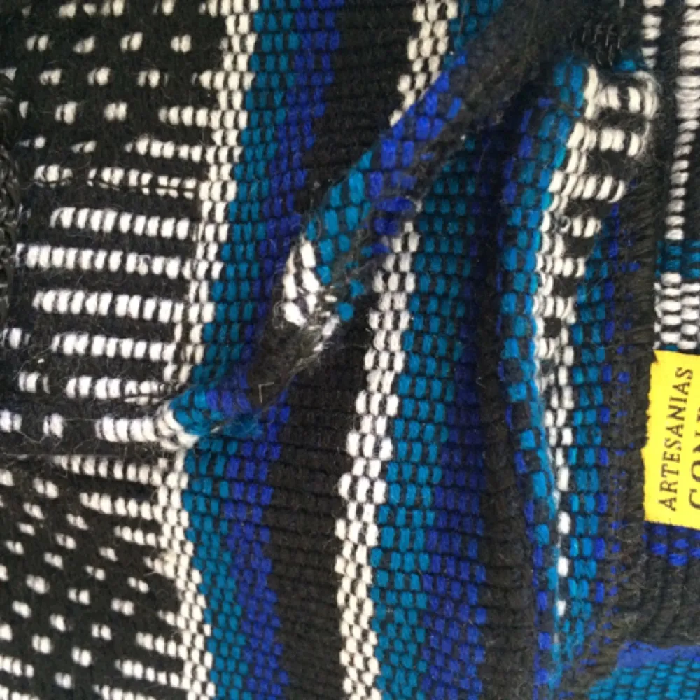 Mönstrad rymlig ryggsäck i blått, vitt och svart som jag tror är handgjord. Ryggsäcken har ett stort fack som stängs med en oval vit plast 