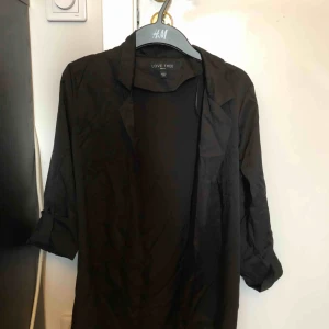  - Svart trenchcoat i skjort material. Köpt från fashion Nova Den har uppkavlade armar som man kan justera 