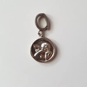  - Berlock med en ängel på i silver. Kan skickas om köparen står för fraktkostnaden som blir 9kr.