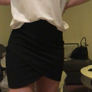  - Svart tight kjol med fin skurning framtill. Säljer även likadan i vit. Använd ett fåtal gånger! Hör gärna av dig för frågor!