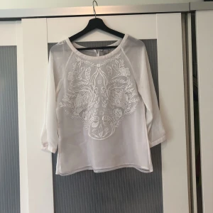  - Jättesöt vit blus från HM. Har ett jättefint broderat mönster på framsidan. Genomskinlig rygg och armar.