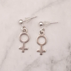 Örhängen med kvinnosymbol *Liten* - Fina silverfärgade örhängen med kvinnosymbolen. Liten symbol. Finns även med större symbol. Se bild nr 3 för storleksskillnad. Nickelfria. 