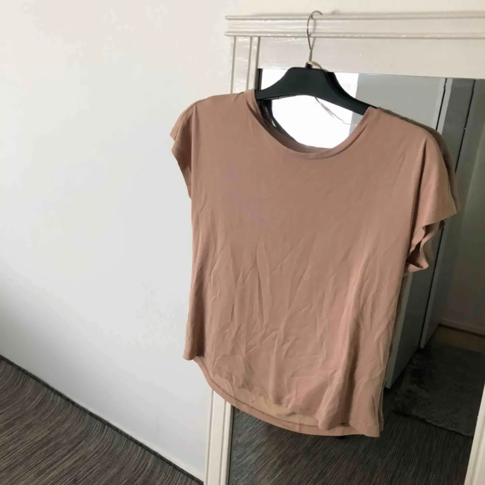 Bärs/nude färgad urringad t-shirt i storlek XS, skulle även fungera som storlek S/M då den är rätt ”luftigt”. Använt endast en gång. Kontakta för fler bilder och frågor! Frakt förekommer.. T-shirts.