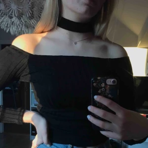  - Svart ribbad offshouldertopp med choker. Använd max 3 gånger, som nyskick! Det är rätt stretchigt material