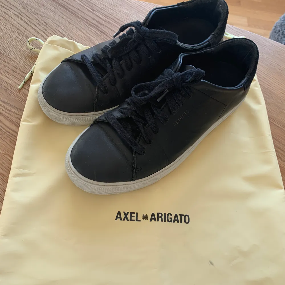 Svarta Axel Arigato sneakers köpta förra sommaren på NK i Göteborg. Använda men i bra skick. Samma gäller dustbagen som kommer till. Lågt pris pga vill bli av med . Skor.