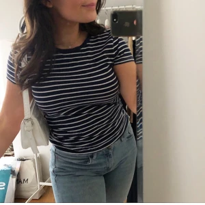 Randig T-Shirt från Tommy Hilfiger - Jag säljer denna blå-vit randiga T-shirt från Tommy Hilfiger. Jätte fräsch nu till sommaren och hösten! Storlek S men passar XXS-M. Säljer på grund av att den inte kommer till användning längre. 💙💙priset är exklusive frakt!!