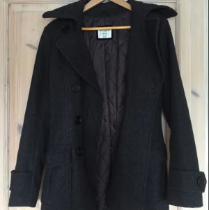  - Snygg höst/vår jacka från H&M i storlek 34. Grå/svart figursydd med krage och två fickor fram samt stora knappar fram och längst ned på armarna. Mycket sparsamt använd. 