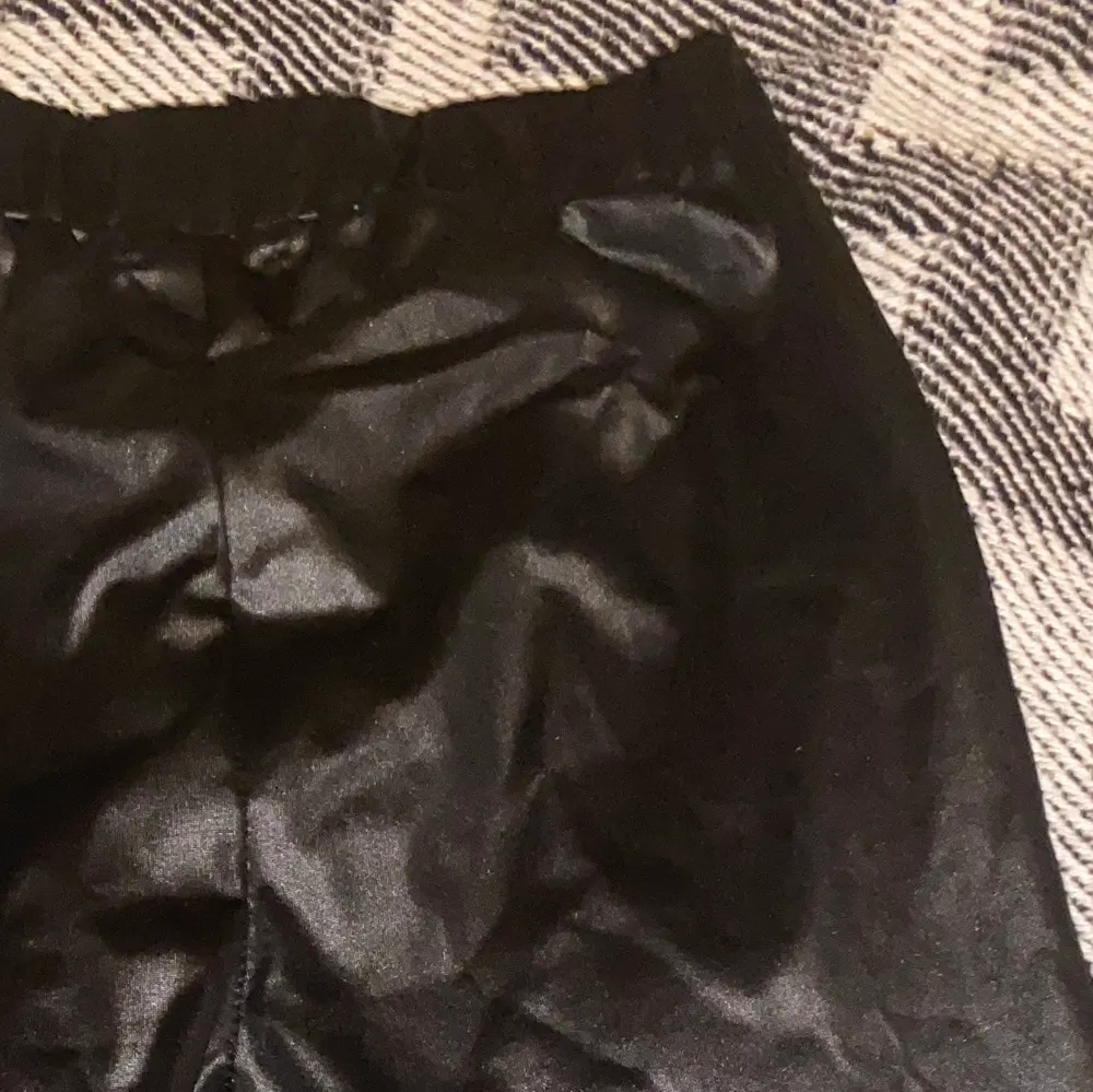 Svarta byxor i glansigt material, typ samma stil som skinnbyxor. Resår i midjan inte använda.. Jeans & Byxor.