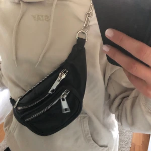 Väska - En svart midjeväska med silver detaljer är i nyskick kan fraktas