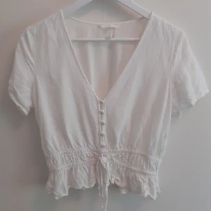 Vit blus/topp - En vit kort blus/topp med knappar. Knappt använd! Frakten ingår i priset💋