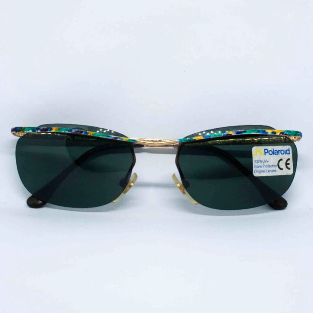 Vintage Y2K 90s 00s Polaroid cyber slim sunglasses in dark green and colorful frame 100% UV+ Barely visible sign of wear, if any Measurements: Frame: 13.5 cm width: 3.8 cm temple: 13 cm Free shipping. Accessoarer.