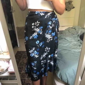  - Svart kjol med blå blommor som man knyter i midjan, använd endast två gånger💘