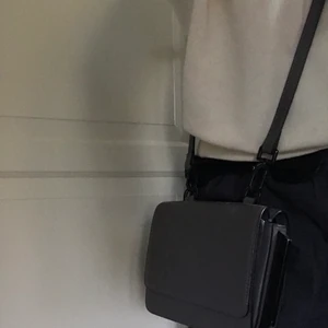 Kendall+Kylie väska - Grå liten väska med två fack, en på vardera sida av bandet. Väskan har inte kommit till användning på över två år och därför bara stått ock samlat damm. Ena spänner har gått sönder (se bild). Det är en liten väska ca 15 • 6 cm 