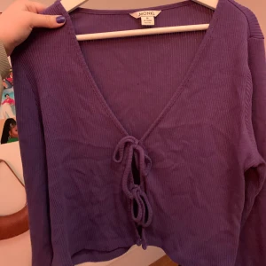 Kofta från Monki strl M - Jättefin lila kofta med dubbel knytning från Monki i storlek M. Använd en gång så i väldigt fint skick. Köparen står för frakt!